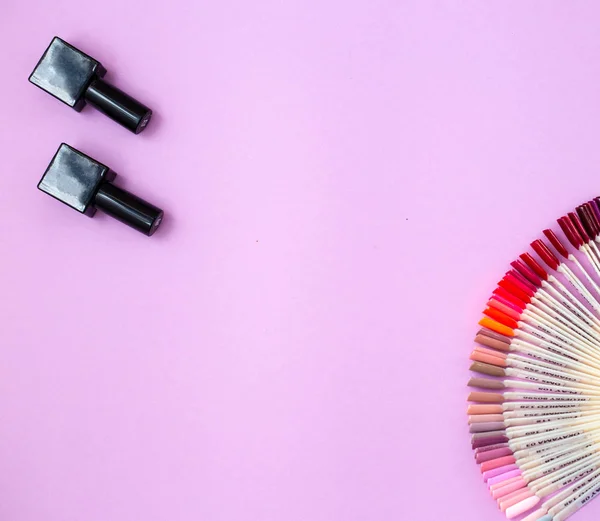 Vista superior de garrafas de esmalte e cores das unhas sobre fundo rosa — Fotografia de Stock