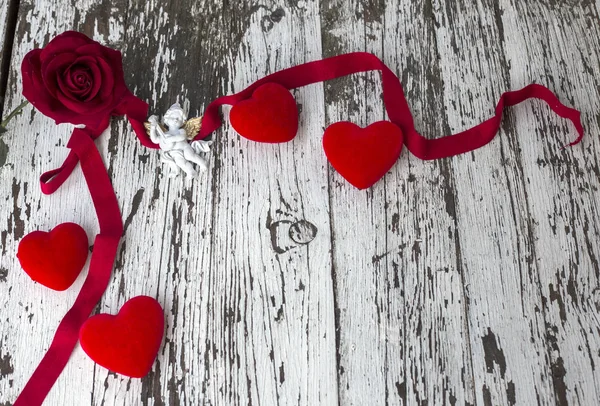 Valentýnská karta s růží, bílým andělem a červenými tvary srdce na dřevěné desce, kopírovací prostor. Pohled shora, byt ležel — Stock fotografie