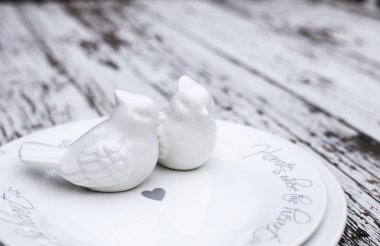 Valentines day romantic table setting with white plates and ceramic birds on white wooden background. Copyspace