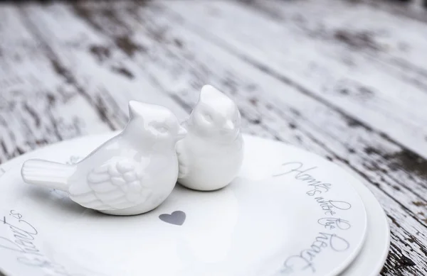 San Valentino romantico tavolo con piatti bianchi e uccelli in ceramica su sfondo bianco in legno. Copyspace — Foto Stock