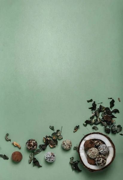 Çiğ protein enerji topları fındıklı, kurutulmuş meyve ve bal hindistan cevizinin yarısında çiçek yaprakları dikey arka planda. Hindistan cevizi kasesi. Boşluğu kopyala, üst görünüm