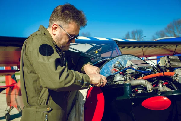 Pilot küçük uçakları tamir ediyor. Havalimanında, çok hafif bir uçağın yanında, uçuş kıyafetli bir adam var. Kitfox 4. Mavi gökyüzüne karşı özel uçağın kendi kendine bakımı