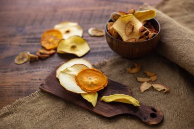 Kurutulmuş organik meyve çerezleri ahşap arka planda kasede. Doğal diyet elma cipsi, kurutulmuş mango, tahta masa üzerindeki ananas çuval bezi. Yatay