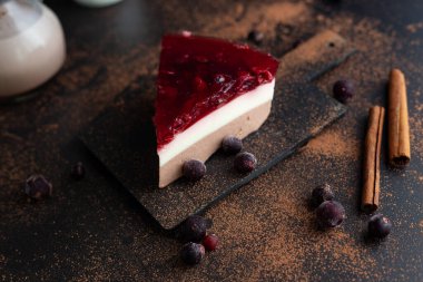 Soya sütü, keçiboynuzu ve meyve jölesinden yapılan diyet katmanlı tatlı siyah kakao ve siyah arka planda tarçınlı, kiraz ve siyah frenk üzümlü. Yaz için sağlıklı bir tatlı..