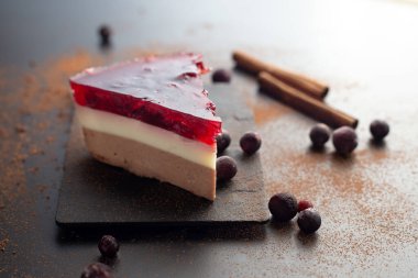 Soya sütü, keçiboynuzu ve meyve jölesinden yapılan diyet katmanlı tatlı siyah kakao ve siyah arka planda tarçınlı, kiraz ve siyah frenk üzümlü. Yaz için sağlıklı bir tatlı..