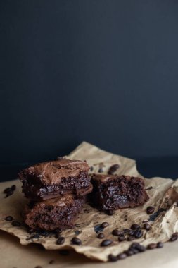 El yapımı çikolatalı kek ve siyah arkaplanlı el yapımı kağıt üzerinde kahve çekirdeği. Kahverengi glütensiz keçiboynuzu keki. Uzayı kopyala, dikey