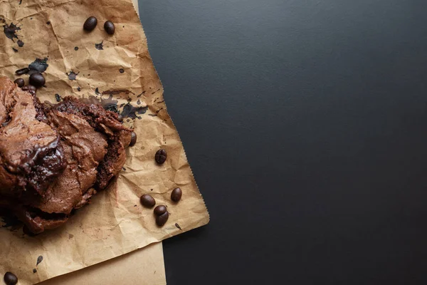 Ev yapımı çikolatalı kek ve siyah arka planda el işi kağıt üzerinde kahve çekirdeği. Kahverengi glütensiz keçiboynuzu keki. Boşluğu kopyala, üst görünüm, yatay