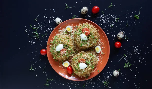 Bıldırcın yumurtalı, domatesli ve mikroyeşilli karabuğday eriştesi. Seçici odaklanma. Peynirli karabuğday makarnası, sebze ve kırmızı tabakta roka malzemeli siyah zemin. Yatay, üst görünüm.