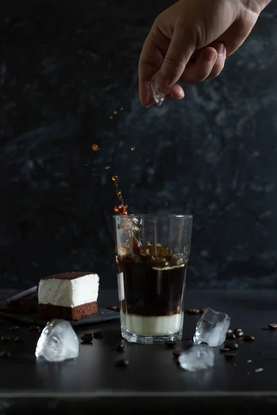 Geleneksel Vietnam kahvesi ile bardağa bir parça buz at. Sufle tatlı ve koyu grunge arka planda buzlu kahve. Su sıçrattı. Alçak tuş, dikey