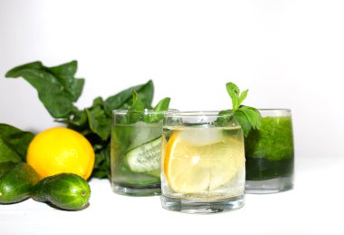Sağlıklı beslenme ve beyaz arka planda kilo kaybı için yeşil ıspanaklı smoothie ve hala salatalık, nane ve limonla detoks suyu harmanlanmış. Yaz sebzesi. Buzlu ve malzemeli sağlıklı bir içecek..