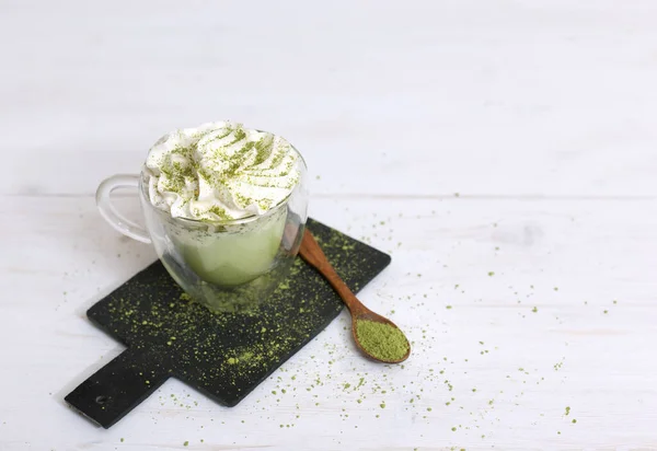 Healthy matcha dessert with aquafaba and mint. Glass cup with spoon on dark board on light background with copy space. Green matcha for vegetarians. Weight loss concept, sugar free dessert