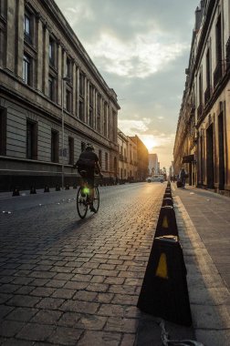 Bisikletçi ışığa doğru giden bir caddeden geçiyor.