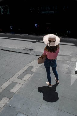 Şapkalı kadın caddenin ortasında bekliyor.