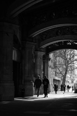 İnsanlar güneş arkadayken köprüden yürüyorlar.