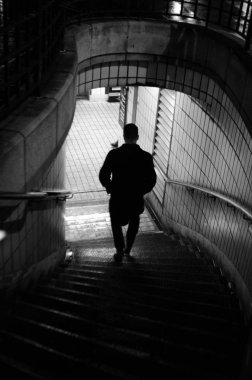 Gece yarısı yarı dairesel bir şekilde merdivenlerden inen bir adamın silüeti.