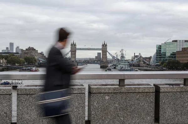 Profile of blurred silhouette of a man walking while looking at an old bridge in the distance