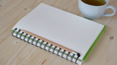 Tahta masada yeşil çay ve defter