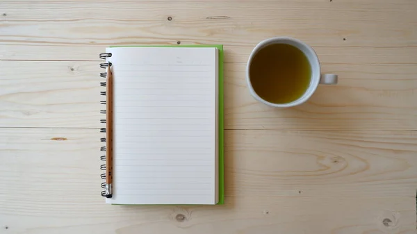 Tahta masada yeşil çay ve defter