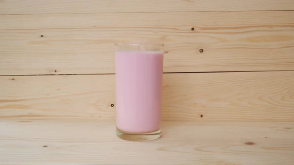 Szklanka Różowego Mleka Drewnianym Stole — Zdjęcie stockowe