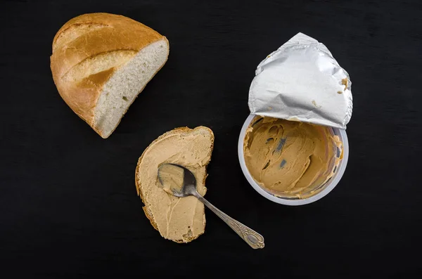 spread hummus on bread on a black background.