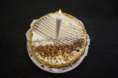 Mumlu lezzetli bir pasta, konsantre süt ve siyah bir masanın üzerindeki bir tabakta haşhaş tohumu. Yakın plan..