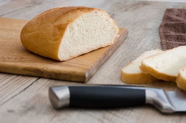 long loaf on a wooden board and knife. Delicious Ukrainian bread. Sliced white bread.