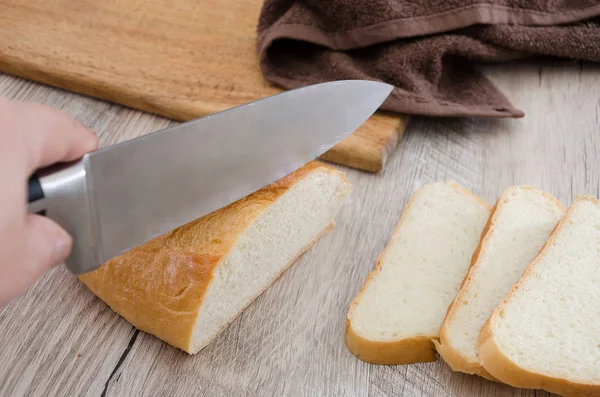 long loaf on a wooden board and knife. Delicious Ukrainian bread. Sliced white bread.