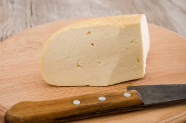 Bir parça tütsülenmiş peynir ve tahta bir arka planda bıçak. Gullsky, Ukrayna peyniri.