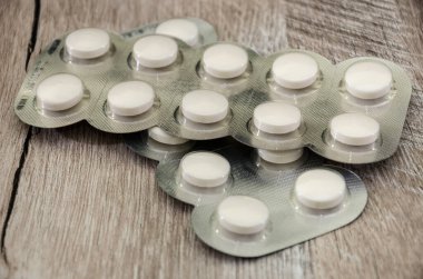 Tahta bir masanın üzerindeki su toplayan pakette beyaz haplar..