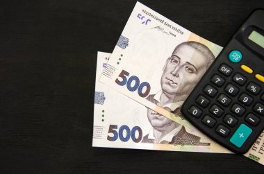 Siyah arka planda Ukrayna hrivnisi ve hesap makinesi. Metin için yer.
