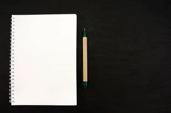 白いノートと黒いテーブルの上にペン テキストのスペース — ストック写真