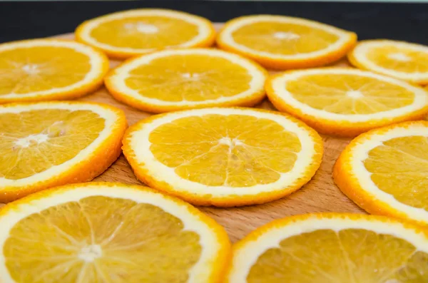 Sliced orange on a wooden board. Juicy orange slices on a board. Orange background.