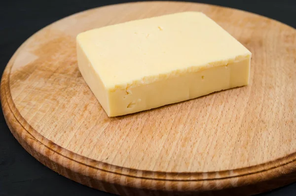 Stück Hartkäse Auf Einem Holzbrett Schwarzer Hintergrund — Stockfoto