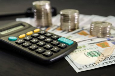 Siyah arka planda dolar, bozuk para ve hesap makinesi. İş konsepti.