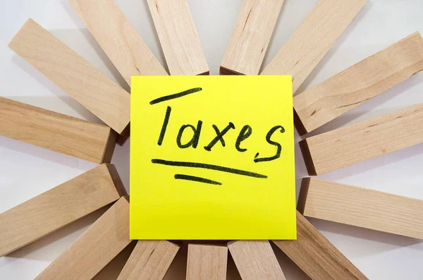 the word taxes on a paper sheet on a background of wooden blocks.