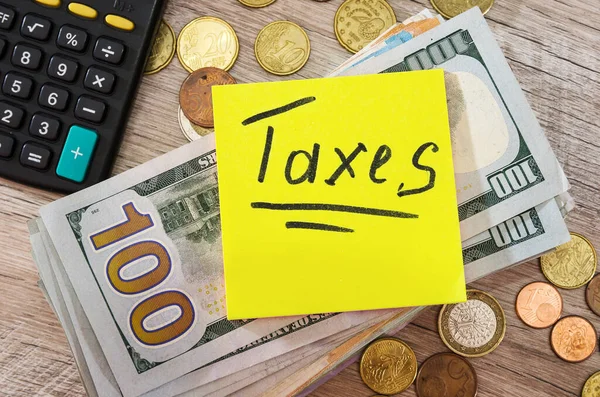 Impostos Inscrição Fundo Uma Pilha Dólares Moedas Uma Calculadora Conceito — Fotografia de Stock