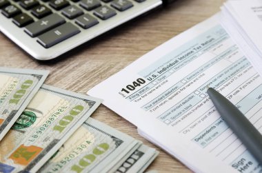 vergi formları 1040, hesap makinesi, dolar ve kalem.