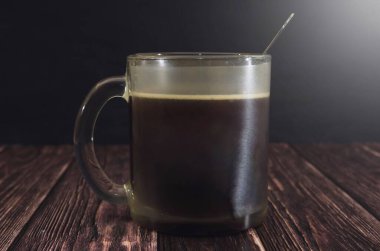 Bir fincan lezzetli kahve ve ahşap bir masada bir kaşık. Görüntü renkli. Günaydın Kahve. Dramatik resim.