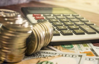 Dolar ve hesap makineli para yığınları. İş konsepti. Para biriktirme kavramı. Madeni para büyümesi. Yakın plan..