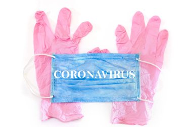 Pembe tıbbi eldiven ve beyaz bir arka planda maske. Enfeksiyon ve virüslere karşı korunma aracı. Maskedeki yazı CORONAVIRUS