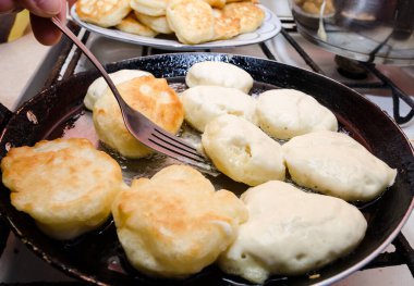 Çörekleri sıcak tavada çatalla çevir. Börek pişirme konsepti. Lezzetli, ev yapımı börek..