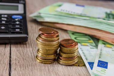 Tahta bir arka planda yığınla para, hesap makinesi ve avro. Yakın plan. İş konsepti.