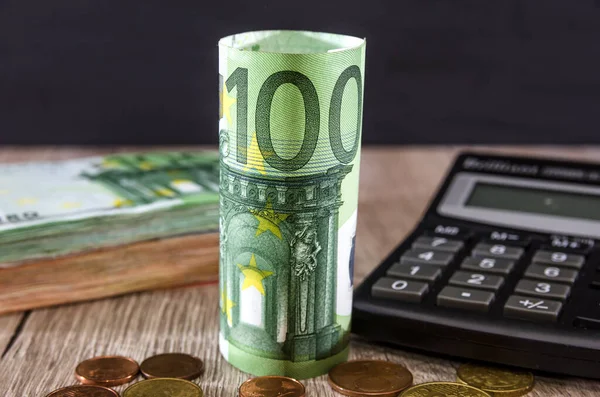 Hesap makinesi, bozuk para ve euro banknotlarının arka planında 100 avro toplandı. İş konsepti.