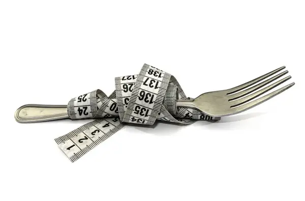 白い背景に測定テープで包まれたフォーク ダイエットと減量の概念 — ストック写真