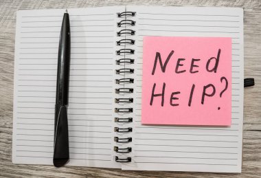 Etikete yazılan yazı, açık bir defter ve siyah bir kalem..