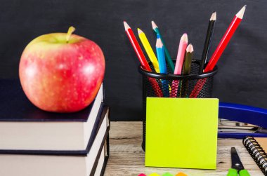 Bir yığın kitabın üzerinde elma ve tahta arka planda renkli kalemler. Eğitim kavramı.