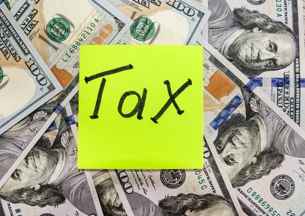 Steuer Auf Einem Gelben Aufkleber Auf Einem Hintergrund Aus Dollars — Stockfoto