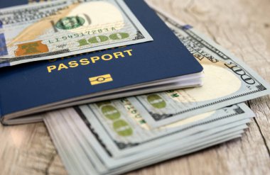 Tahta bir masanın üzerindeki pasaportun içinde dolar var. Yakın plan..