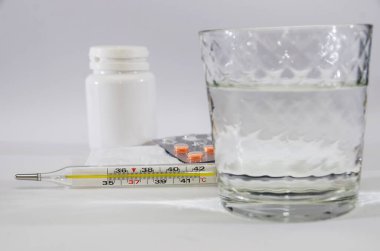 İlaçlar ve beyaz üzerine bir bardak su. Yakın plan.