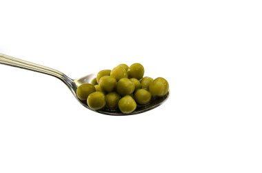 Beyaz arka planda izole edilmiş kaşıktaki yeşil bezelyeler..